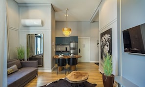 A modern living room with a sofa, a dining table with chairs, a chandelier, and a large painting on the wall. - Elegant apt in the Heart of Gramado Cbg0106 (Gramado)
