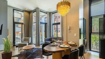 A modern dining area with a wooden table, black chairs, and a chandelier.