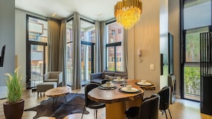 A modern dining area with a wooden table, black chairs, and a chandelier. - Elegant apt in the Heart of Gramado Cbg0106 (Gramado)