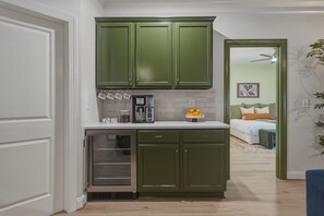 Una cocina con armarios verdes, una cafetera y un frutero.