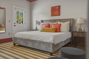Un dormitorio con cama, lámparas de noche, un espejo y una ventana.