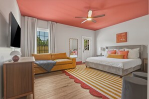 Un dormitorio con cama, sofá, televisión y ventilador de techo.