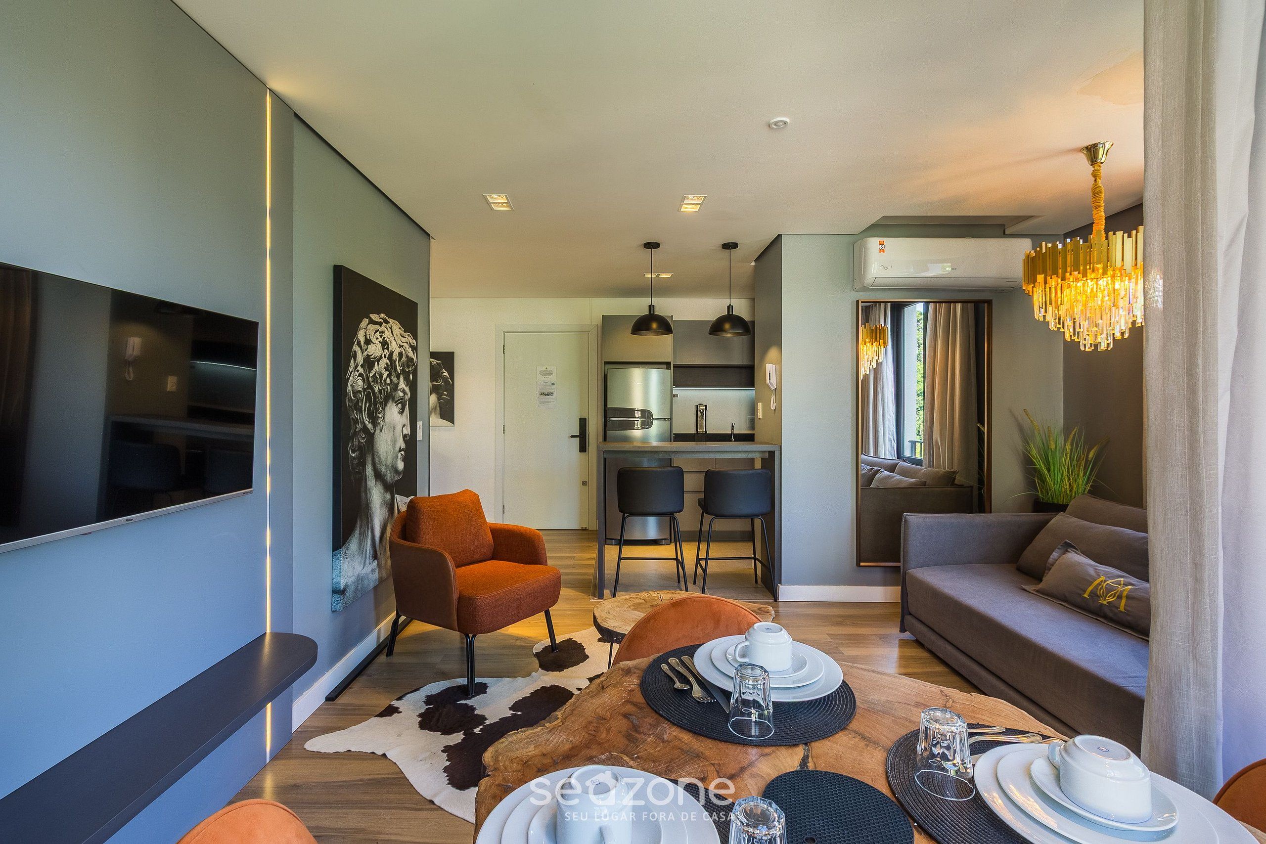 A modern living room with a sofa, a dining table set, and a kitchen in the background.