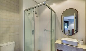 Un bagno moderno con doccia vetrata, lavandino bianco e uno specchio grande.