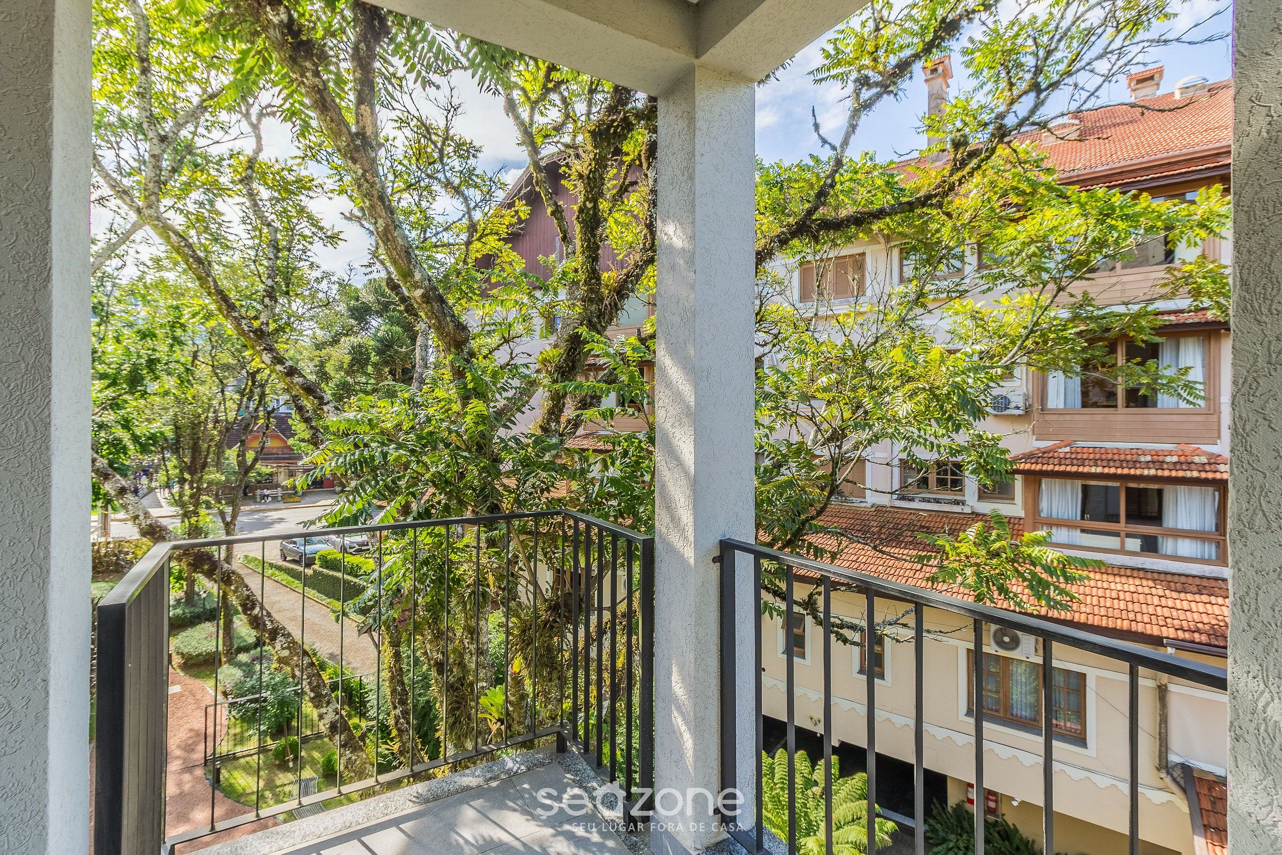A balcony with a view of a garden and neighboring buildings.
