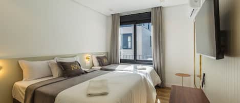 Una habitación de hotel moderna con dos camas, un televisor de pantalla plana y una pequeña mesa.