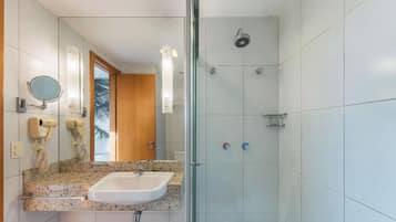 Une salle de bain avec une douche à parois de verre, un lavabo avec un miroir et un porte-serviettes.