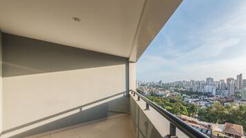 A balcony with a city view, a tiled floor, and a metal railing.