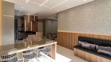 A modern kitchen with a dining area, featuring a long countertop and bar stools.