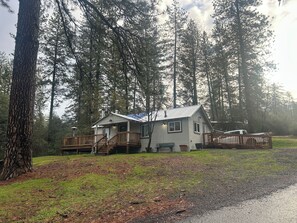Een chalet met een terras, omringd door hoge bomen.