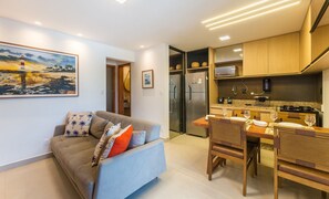 Un espacio habitable compacto con sofá, mesa de comedor y zona de cocina.