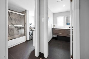 A modern kitchen with a built-in washing machine, a marble backsplash, and a dark tiled floor.