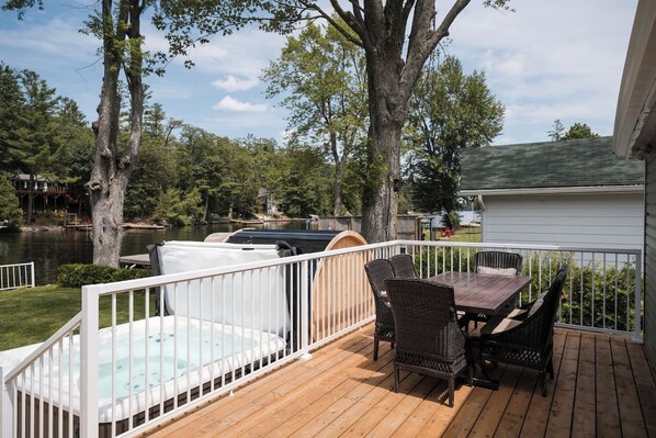 A deck with a hot tub, outdoor furniture, and a view of a lake.
