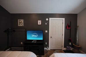 A hotel room with a bed, a television displaying the Disney+ logo, a door, and a wall-mounted light switch. - Washago Waterfront: Hot Tub, Sauna, Trails, Fish (Washago)