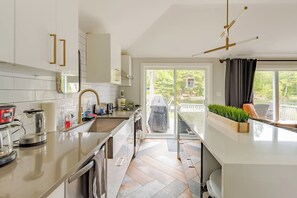 A modern kitchen with a built-in oven, a coffee maker, and a grill outside. - Washago Waterfront: Hot Tub, Sauna, Trails, Fish (Washago)
