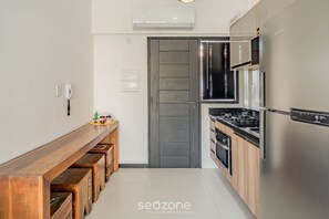 Eine moderne Küche mit integriertem Herd, einem Edelstahl-Kühlschrank und einer hölzernen Sitzbank.