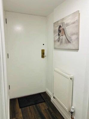 A white door with a brass handle, a radiator below it, and a doormat on the floor.