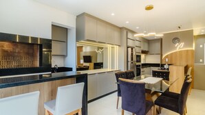 A modern kitchen with a central island, built-in appliances, and a dining area with chairs and a table. - Apt w/ Private BBQ 90m From the Sea Rih0802 (Porto Belo)