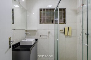 Ein Badezimmer mit Waschbecken, Spiegel und Duschkabine.