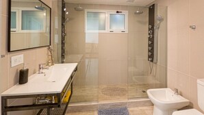 Une salle de bain moderne avec une douche à parois de verre, un lavabo blanc et un bidet.