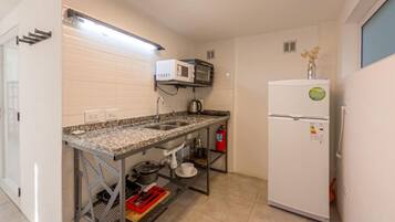 Cocina compacta con microondas integrado, refrigerador y lavamanos.