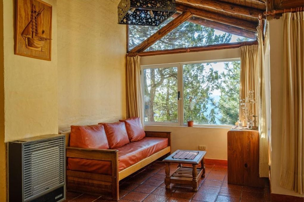 A cozy room with a wooden sofa, a small table, and a window with curtains.