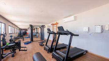 A gym with treadmills, weight machines, and a bench.