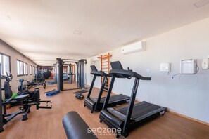 Ett gym med löpband, styrketräningsmaskiner och en bänk.