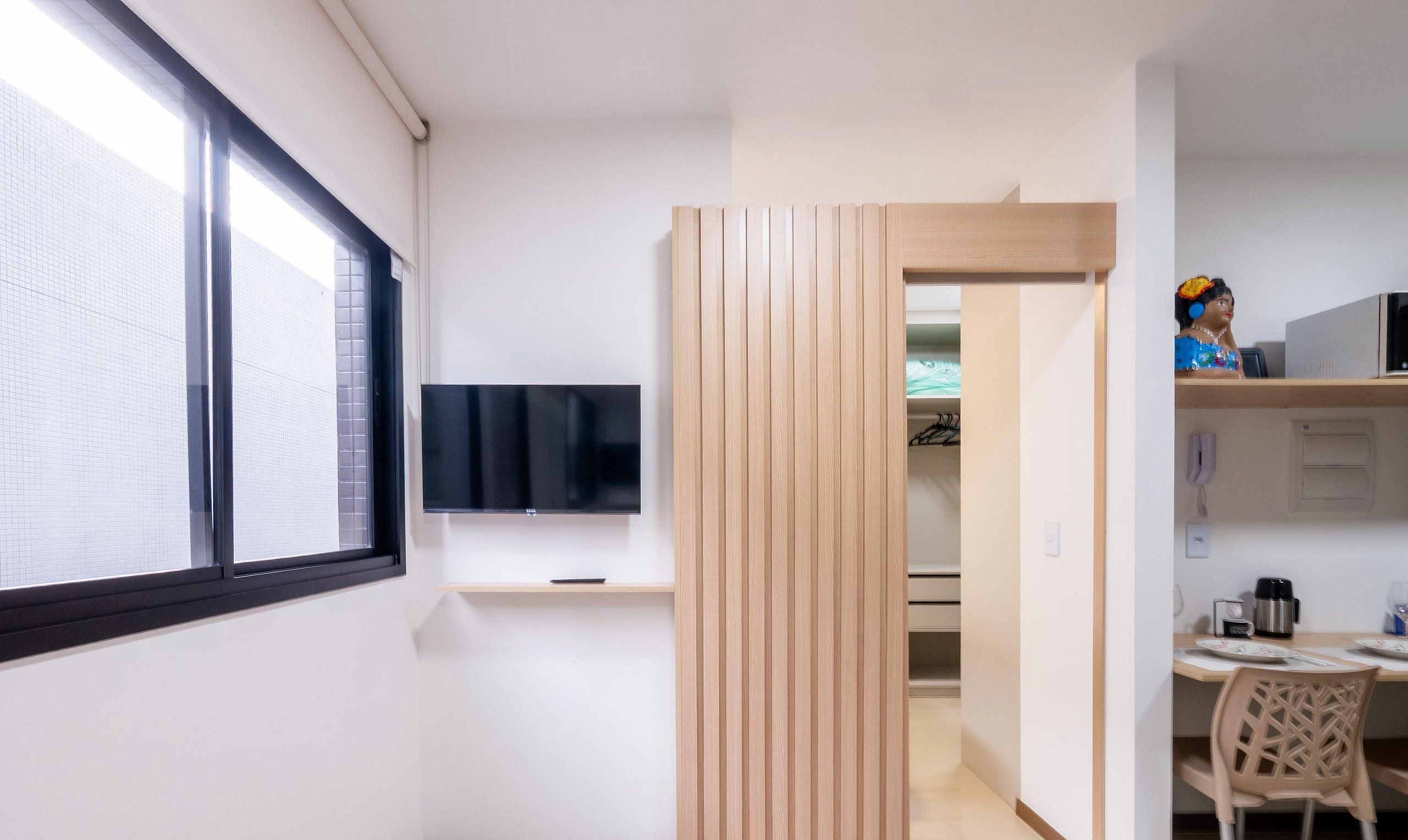 Ett modernt kök med en inbyggd TV, träpanel och en matplats med bord och stolar.