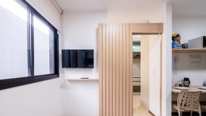 Et moderne køkken med indbygget TV, træpaneler og et spiseområde med bord og stole.