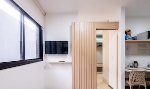 Una cuina moderna amb televisió integrada, panells de fusta i zona de menjador amb taula i cadires.