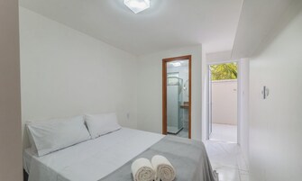 Quarto com cama, travesseiros, toalha e vista para um banheiro e o exterior.