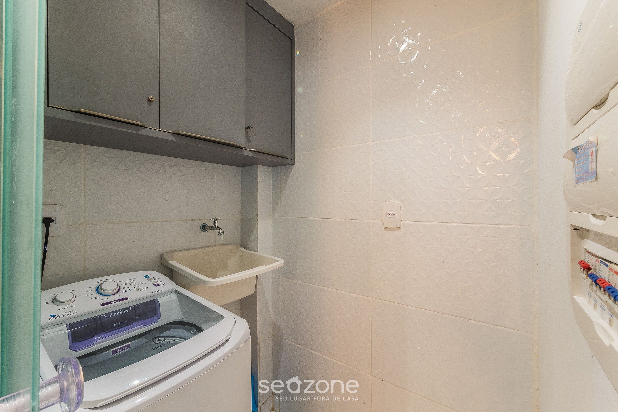A laundry area with a washing machine, a sink, and cabinets.
