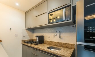 Uma cozinha moderna com micro-ondas embutido, geladeira de aço inoxidável e bancada de granito.