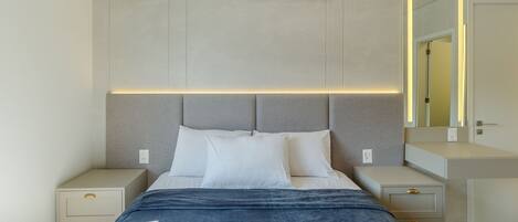 A modern bedroom with a bed, bedside tables, a nightstand, and a wall-mounted air conditioner.