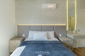 Un dormitorio moderno con una cama, mesitas de noche y un aire acondicionado instalado en la pared.