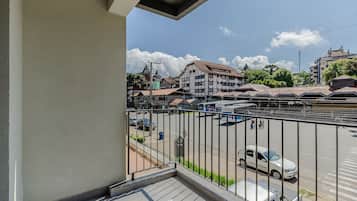 A balcony with a view of a street, buildings, and parked cars.
