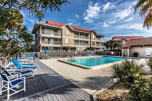 Ein Hotel mit Pool, mehreren Balkonen und einer Terrasse mit Liegestühlen.