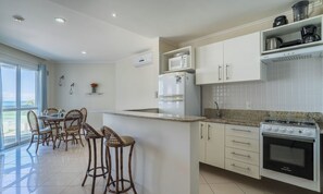 A modern kitchen with a central island, white cabinetry, and a De Ville stove. - Apt. w/ BBQ in Beachfront Condo Pom0113 (Florianópolis)