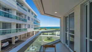 A multi-story building with balconies overlooking a landscaped area and a view of the sea.