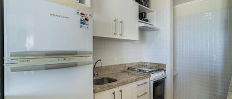A kitchen with white cabinets, a stainless steel sink, a stove, and a microwave.