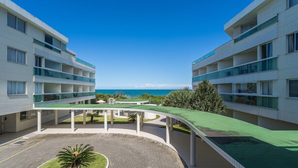 Un hotel moderno con un patio central, varios balcones y vistas al mar.