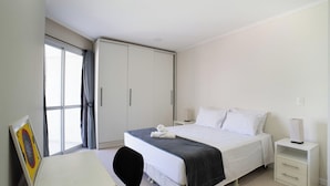 Ein Hotelzimmer mit einem Bett, Nachttischen, einem Schreibtisch und einem Kleiderschrank.
