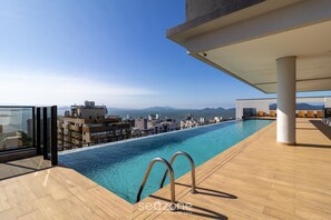 Uma piscina infinita no terraço com vista desobstruída da cidade e das montanhas.