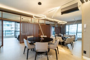 Uma área de jantar moderna com mesa redonda, cadeiras e iluminação pendente.