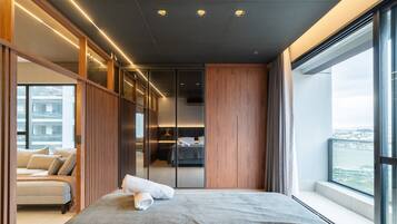 A modern bedroom with a large bed, a view of the city, and a sliding door leading to a bathroom.