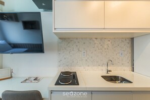 A compact kitchen with a built-in stove, a sink, and a flat-screen TV mounted on the wall. - Studio in Bldg. Oceanfront in Salvador Sma0216 (Salvador)