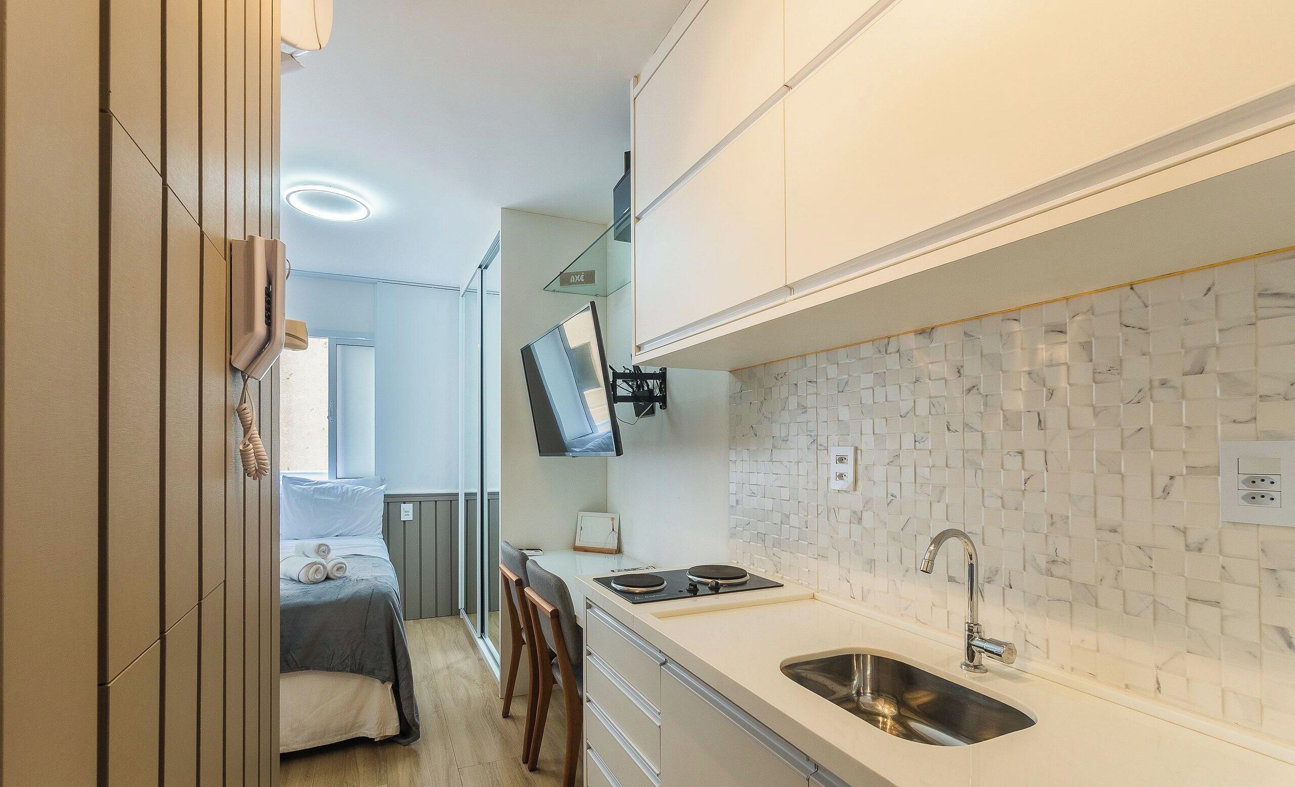 A compact kitchen with a built-in stove, a sink, and a small dining area with a table and chairs.