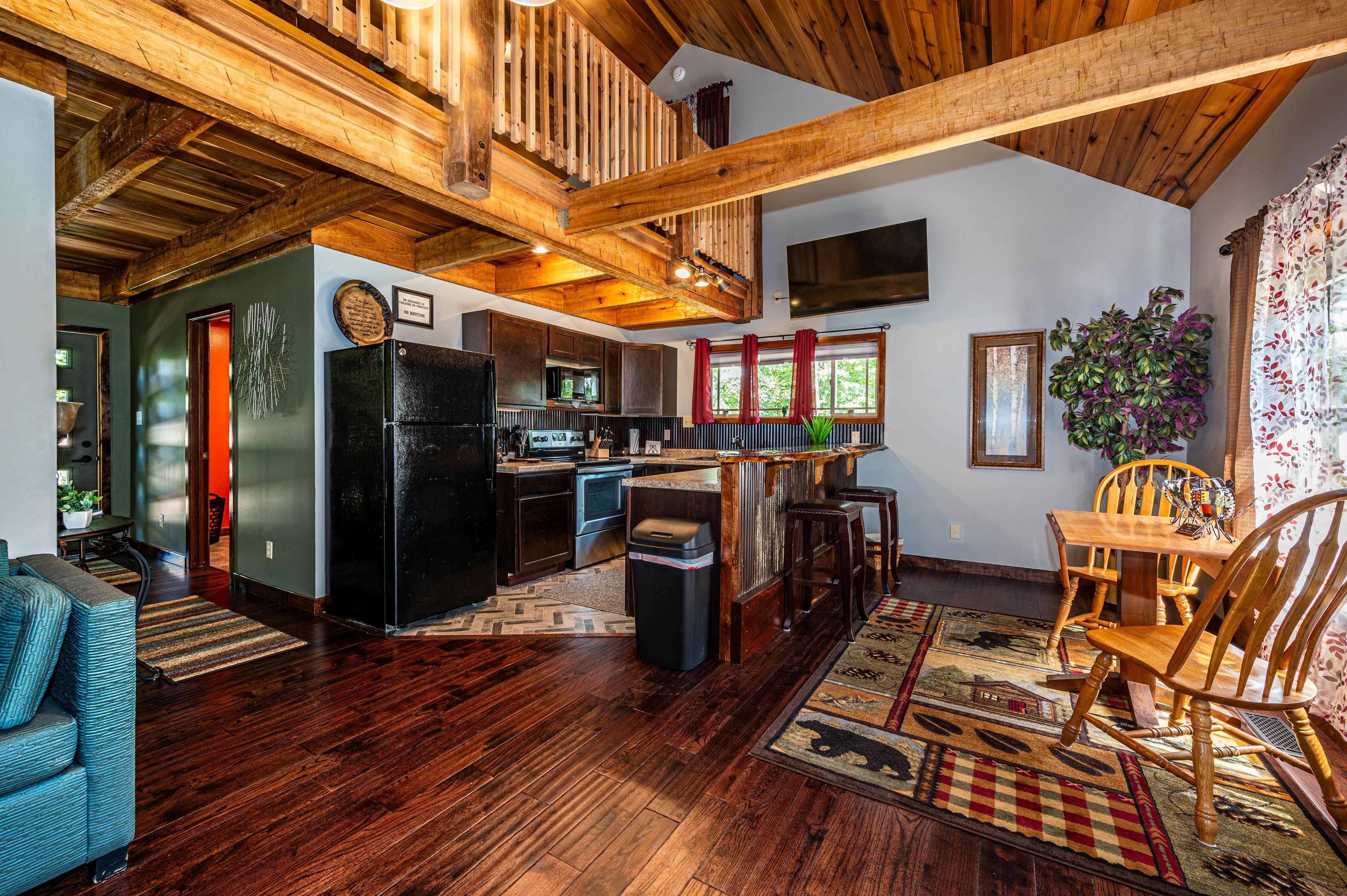 A spacious kitchen with wooden beams, a dining area with a table and chairs, and a living room with a sofa.