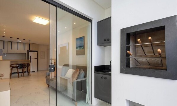 A modern kitchen with a glass partition, a dining area with chairs, and a sofa. - Apt w/ Barbecue, 500m From the Beach Stw1506 (Itapema)